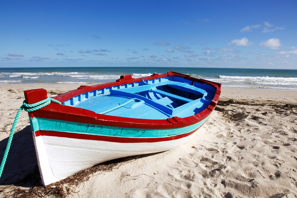 Mała łódź na plaży nad Morzem Śródziemnym, wyspa Djerba, Tunezja.